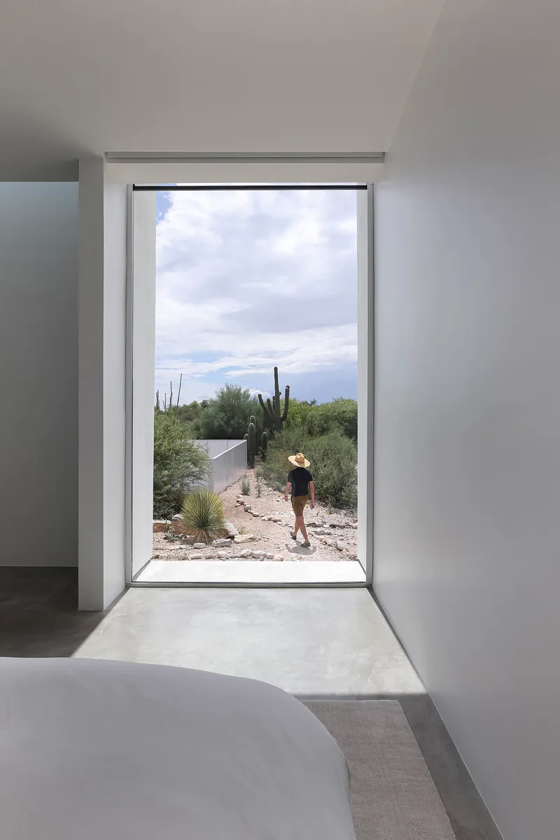 Interior doorway framing a figure in the desert landscape with cacti visible in afternoon light