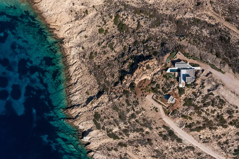 Aerial view of the stone and concrete structures nestled into rocky coastal terrain above turquoise water