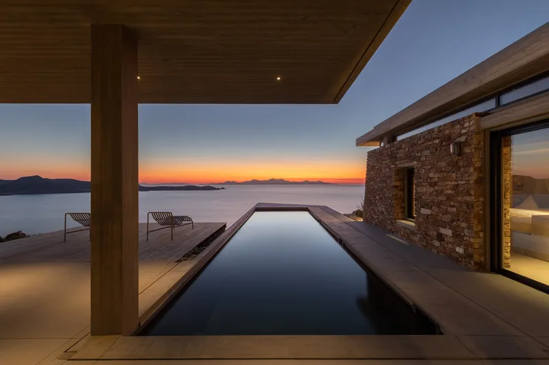 Infinity pool on timber deck beneath a wooden canopy at sunset overlooking the sea
