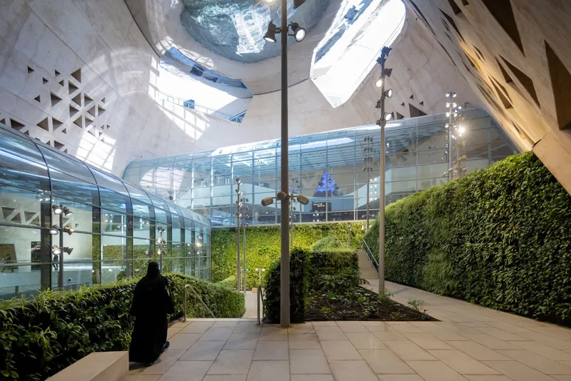 Interior courtyard with planted beds and living green walls beneath a sculptural concrete dome with skylights