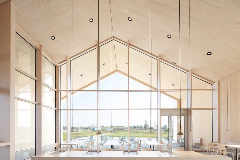 Interior view of the gable window wall with timber mullions and plywood ceiling overlooking the landscape