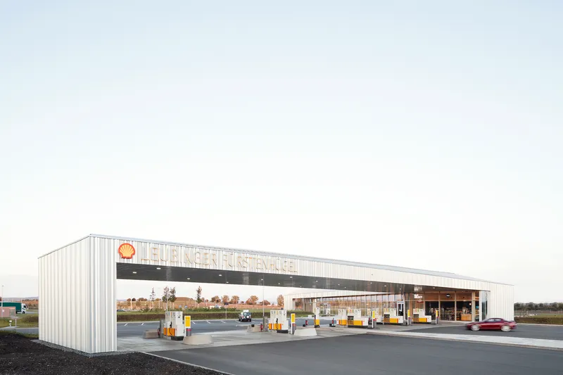 White corrugated metal canopy over fuel pumps at a service station in flat farmland