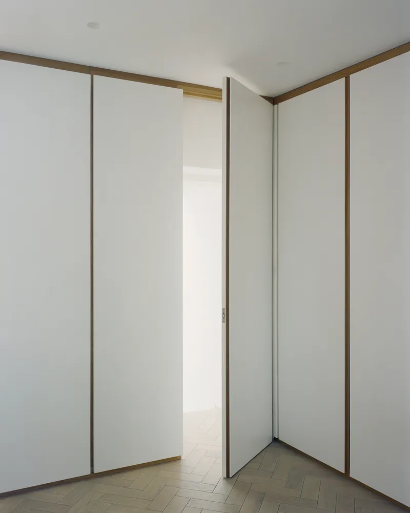 Corner of white room with floor-to-ceiling sliding panels framed in timber edging