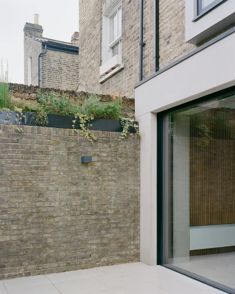 Rear courtyard with weathered brick boundary wall and planted metal planter boxes