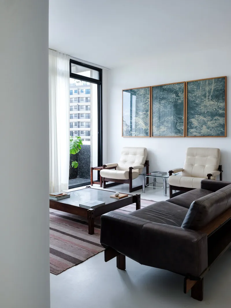 Seating area with leather furniture facing a glazed door opening to a planted terrace