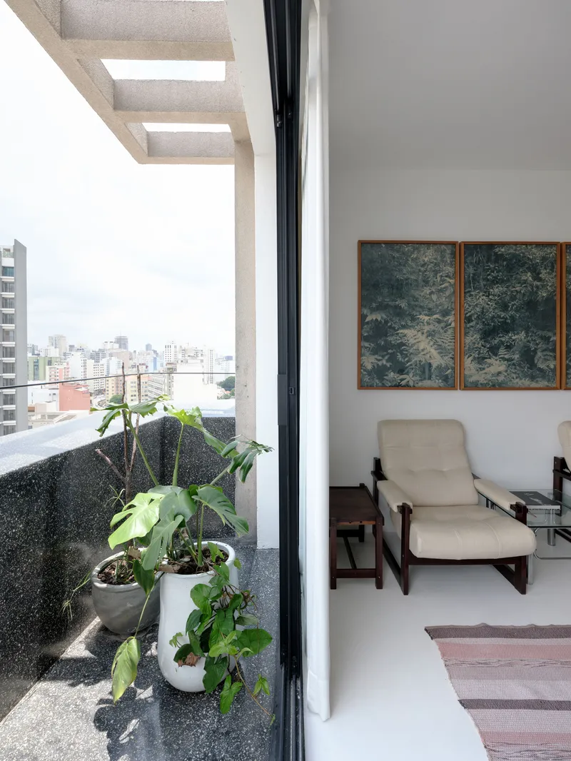 Terrace with potted plants in gravel bed viewed from interior through open glass door