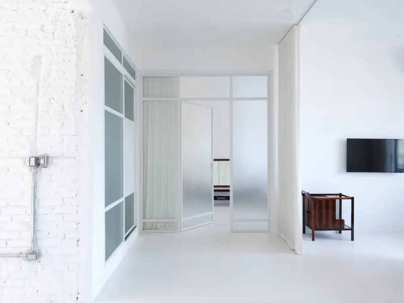 View down corridor toward translucent partition showing glimpse of kitchen beyond