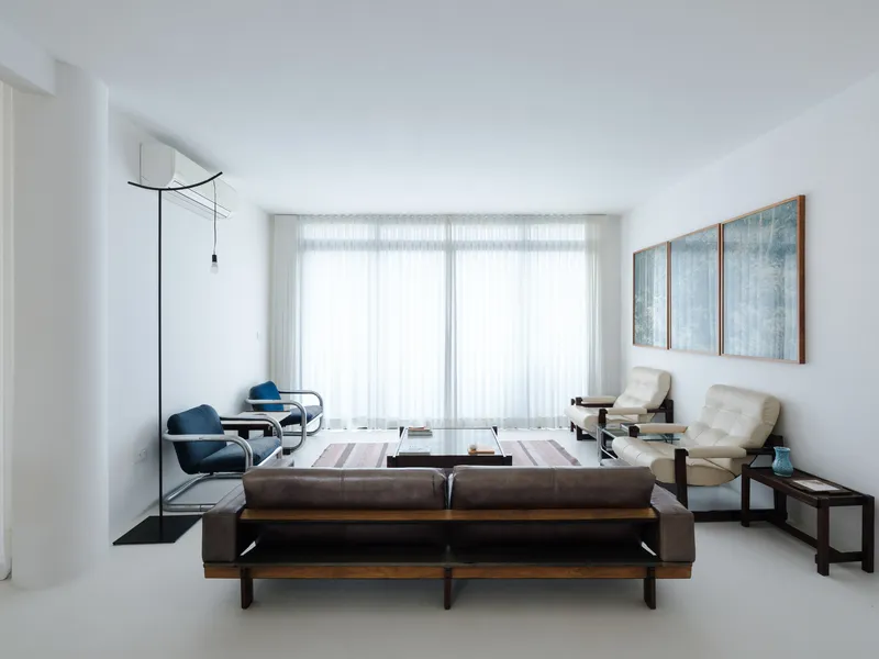 Living room with white sheer curtains spanning curved window wall and mid-century furniture on pale resin floor