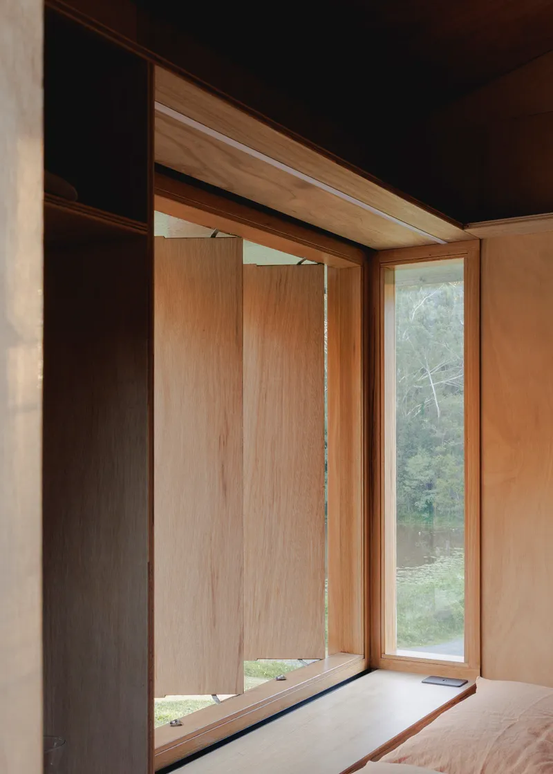 Corner window detail with timber frame and plywood reveals in the sleeping area