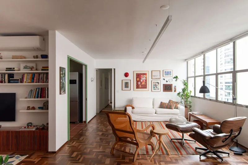 Living room with herringbone parquet floor, built-in shelving, and floor-to-ceiling windows overlooking the city