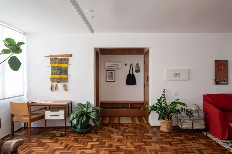 Custom timber entry niche with coat hooks and storage drawers flanked by potted plants