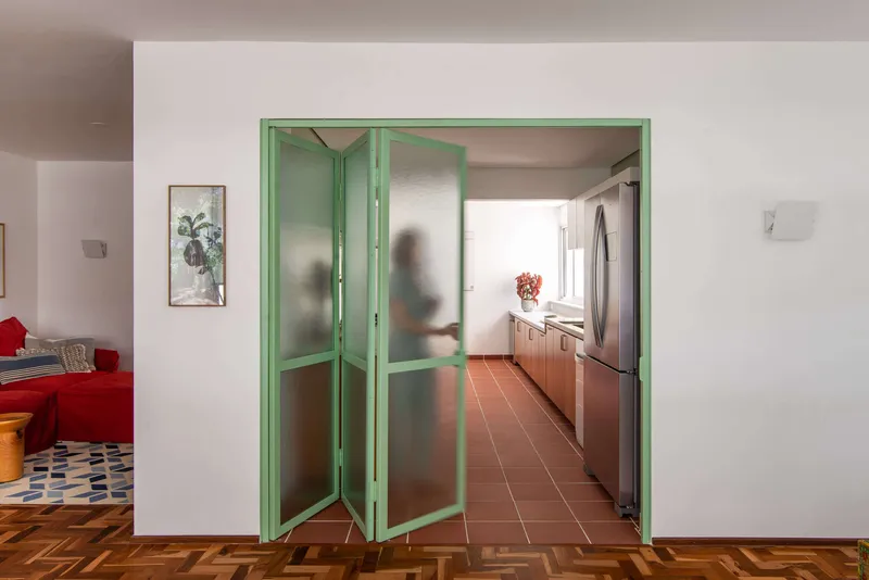 Folding translucent glass doors in pale green frames with figure moving through the kitchen beyond