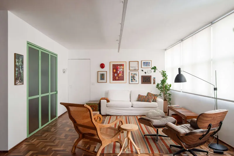 Living room with herringbone wood floor, green-framed sliding door and white roller shades filtering daylight