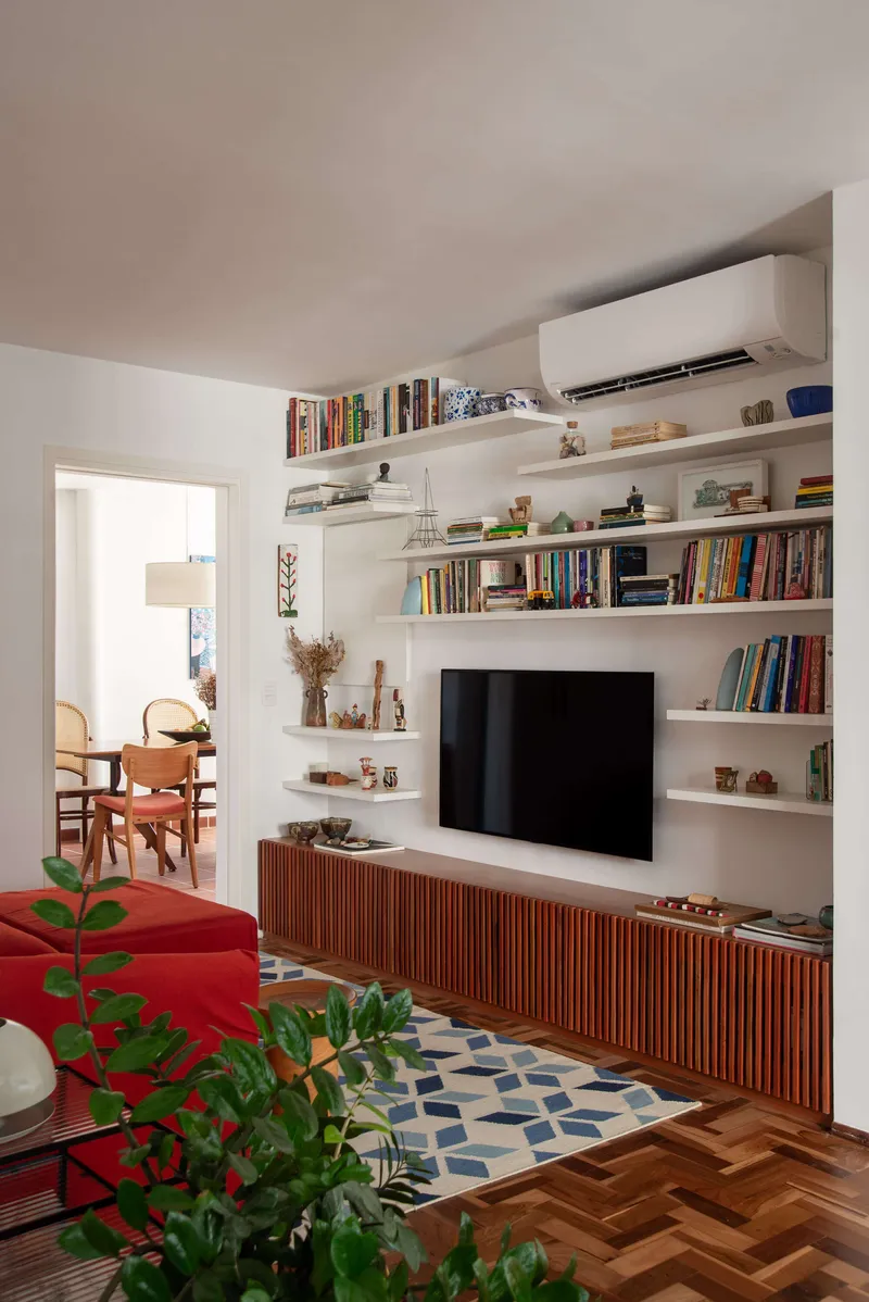 Built-in media wall with floating white shelves above a slatted wood cabinet beneath mounted television