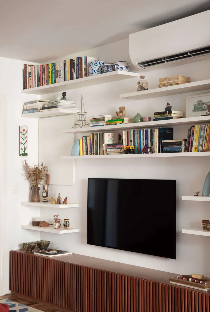 Close-up of the corner shelving unit wrapping around the television with books and objects displayed