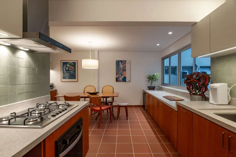 Kitchen with terracotta floor tiles and view to dining area at dusk
