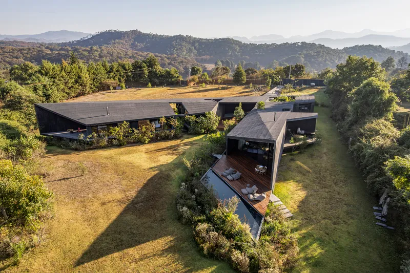 Drone view showing the cantilevered roofs and timber pavilion surrounded by lawn and scattered trees