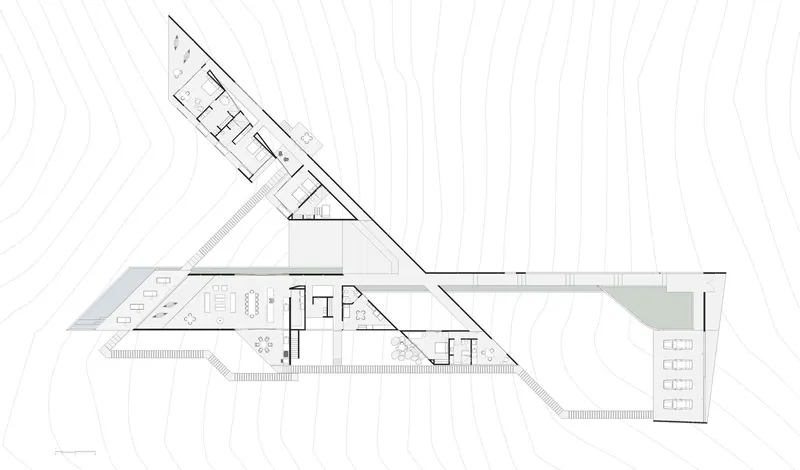 Floor plan drawing showing two angular wings intersecting at a central core with topographic contours
