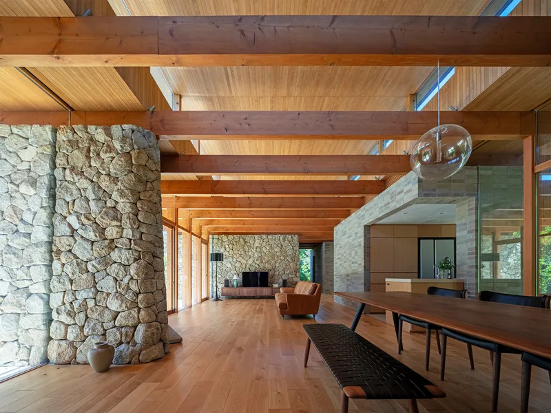 Interior with rough stone column, exposed timber ceiling structure and clerestory windows admitting daylight