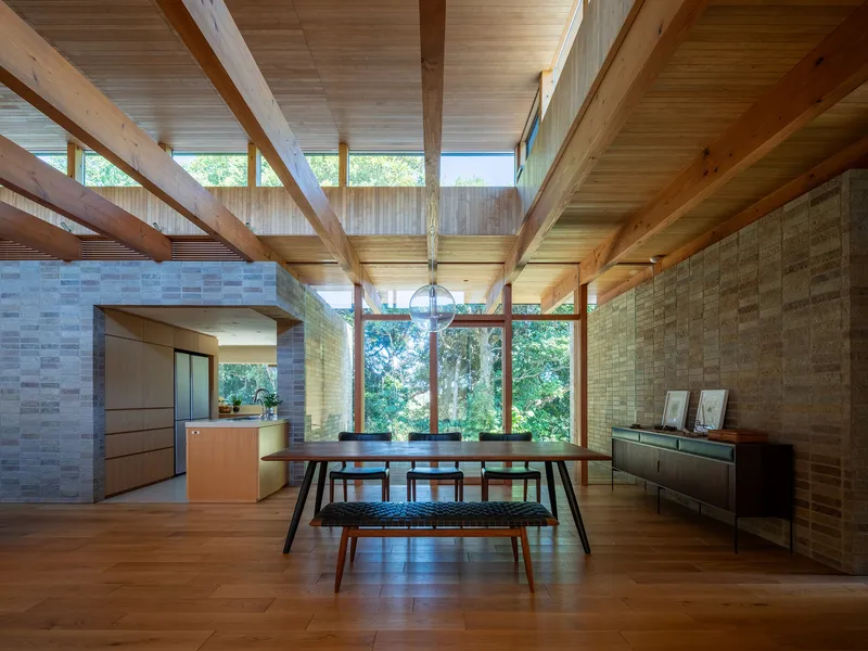 Dining room with exposed timber ceiling structure and clerestory windows overlooking garden