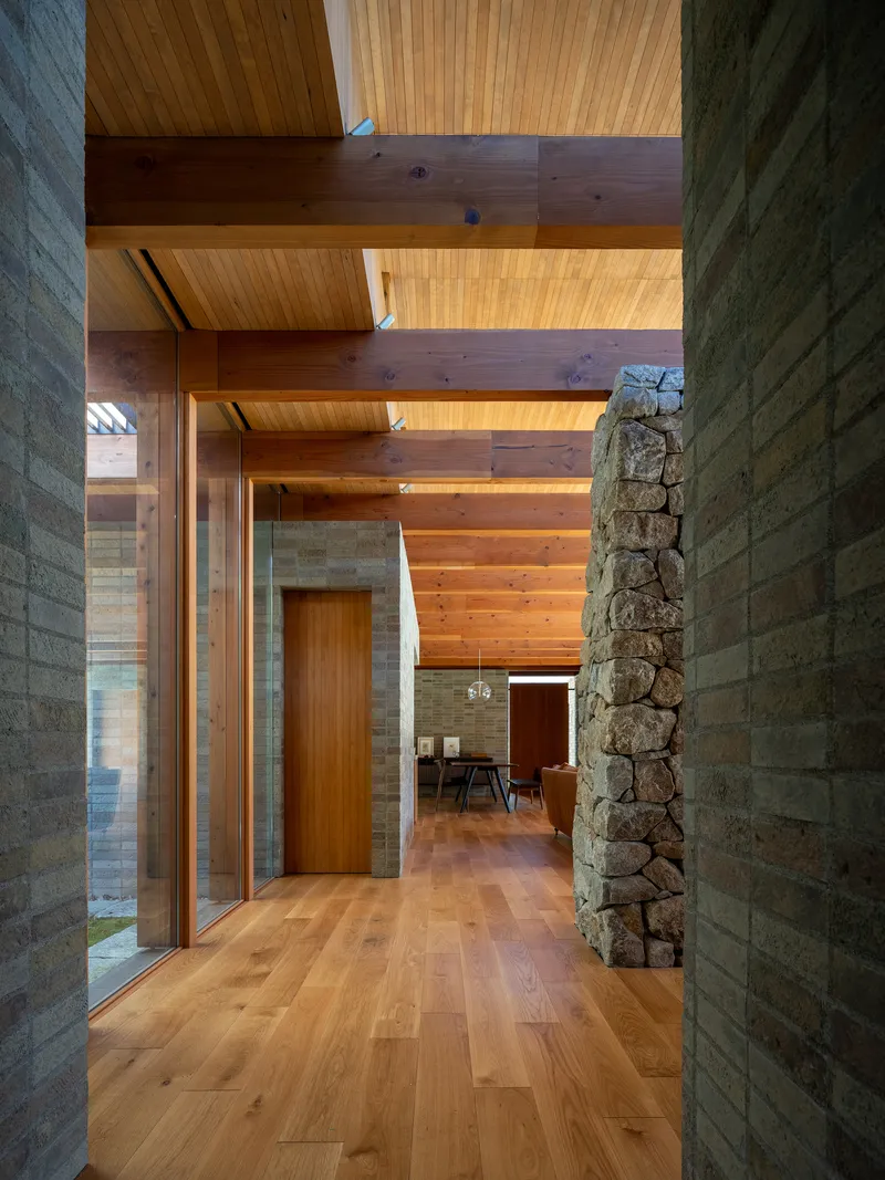 Hallway with fieldstone column and concrete block walls beneath exposed timber beams