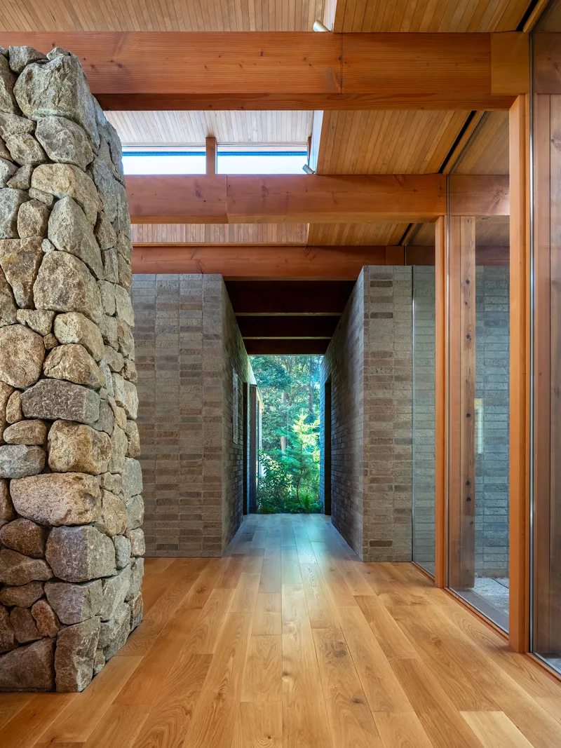 Interior corridor framing a distant window view through layered masonry walls and timber ceiling