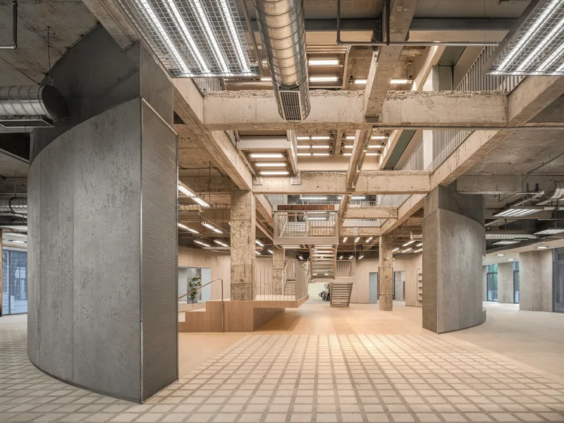 Interior with exposed concrete beams, cylindrical columns wrapped in timber slats, and patterned floor tiles