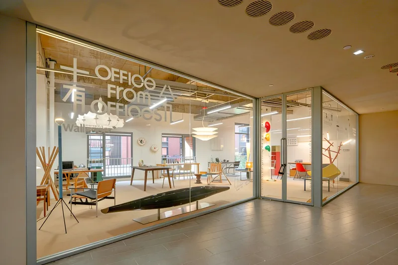 Glass storefront with folding doors opening onto a furniture showroom with white text on the window