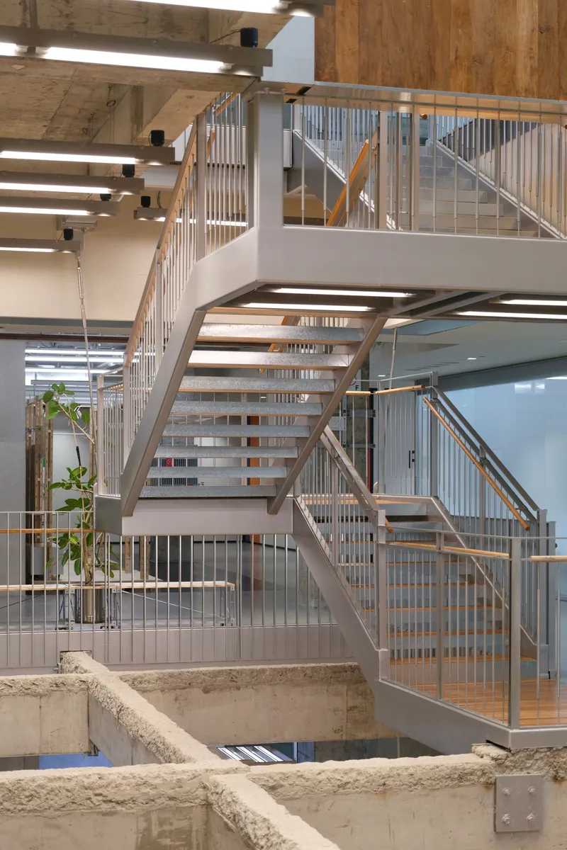 Steel staircase with vertical bar railings crossing over a concrete pit edged with brass railings
