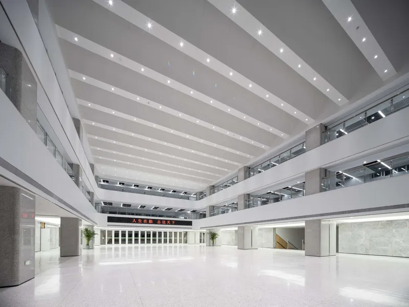 Multi-story interior atrium with white terrazzo floors and horizontal ceiling bands with integrated lighting
