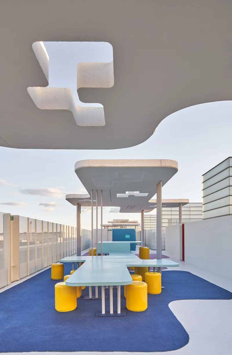 Rooftop terrace with white table, yellow seating, and layered concrete canopies with cutout skylights