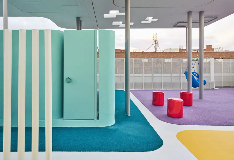 Turquoise flooring with striped partition screens and white columns beneath a grey soffit