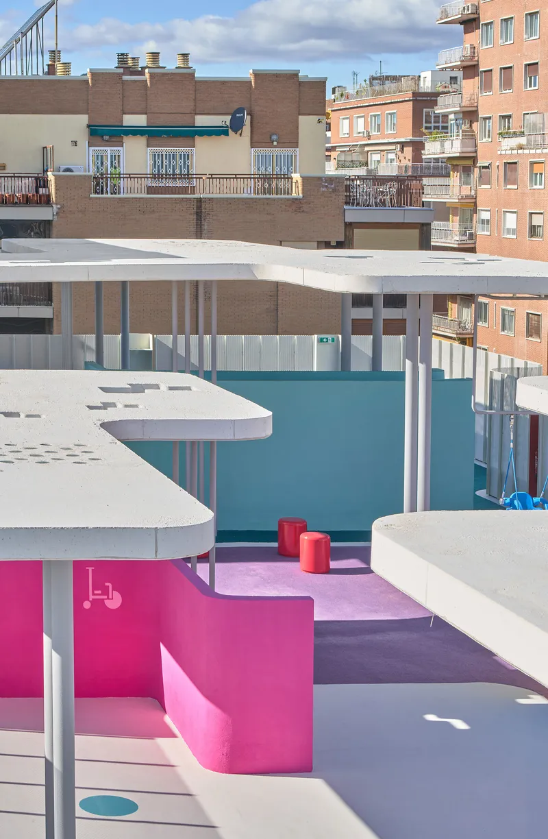 Pink bench and seating area beneath curved roof planes with surrounding residential buildings visible