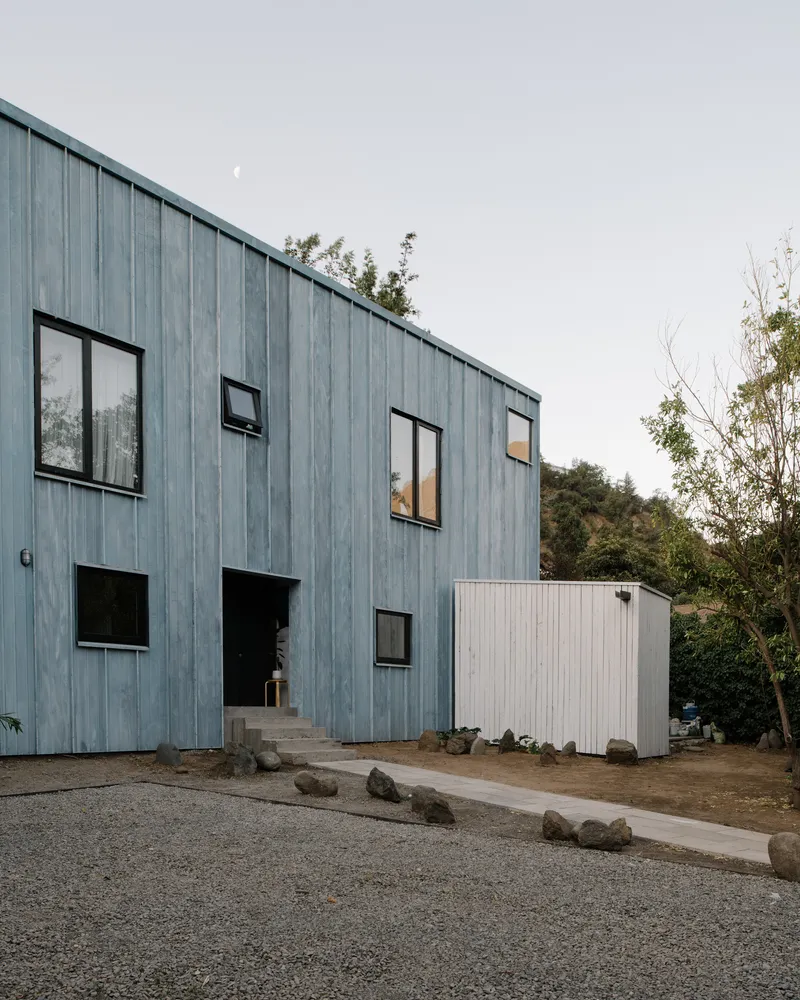 Vertical timber cladding facade with scattered windows and concrete entry steps under overcast sky