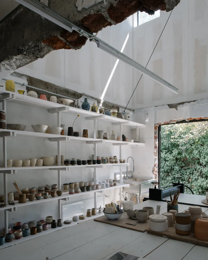 Pottery workshop with white shelving and exposed brick openings under skylit ceiling