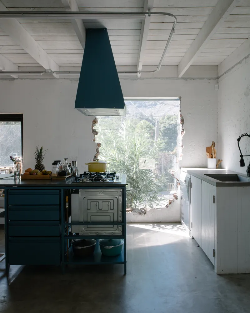 Kitchen with dark blue hood and range framed by a wide window opening