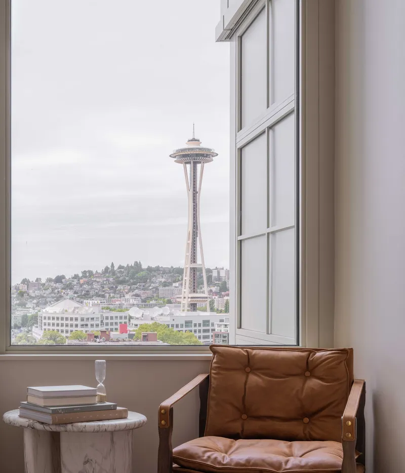Corner window framing a tower landmark beyond the low-rise neighborhood under overcast skies