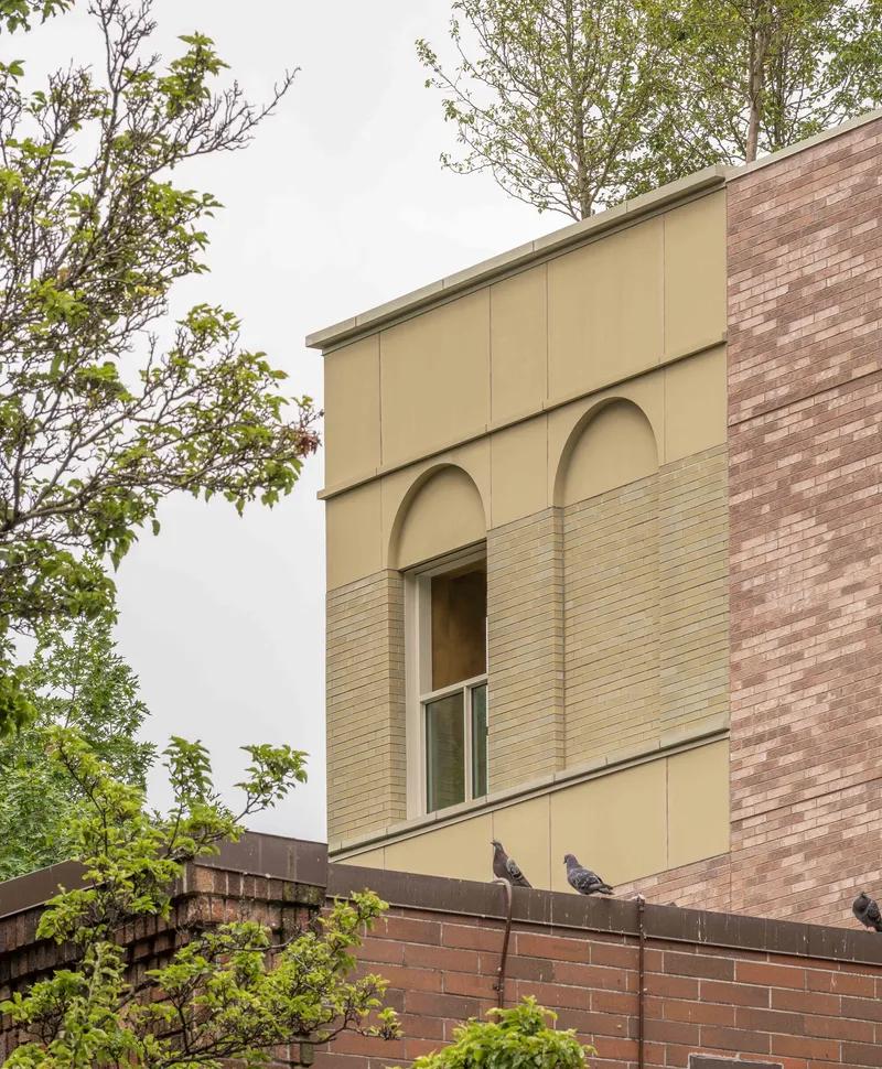 Facade detail with arched openings and horizontal banding flanked by brick wall with pigeons perched