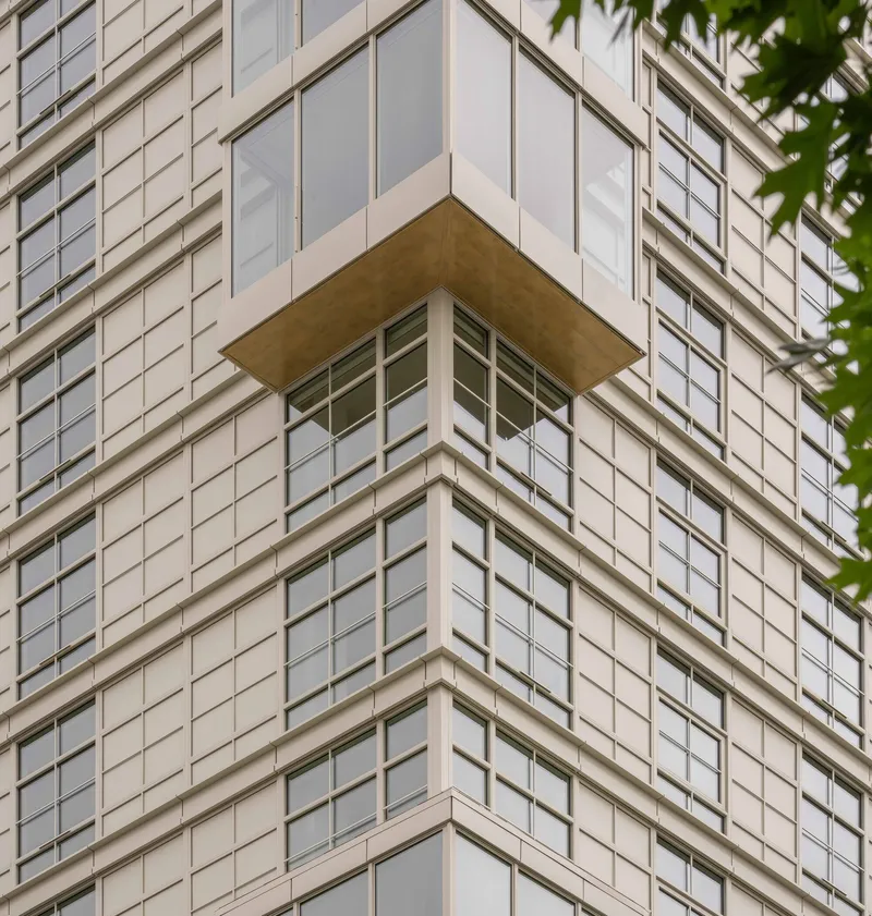 Corner balcony detail with timber soffit projecting from gridded white panel facade