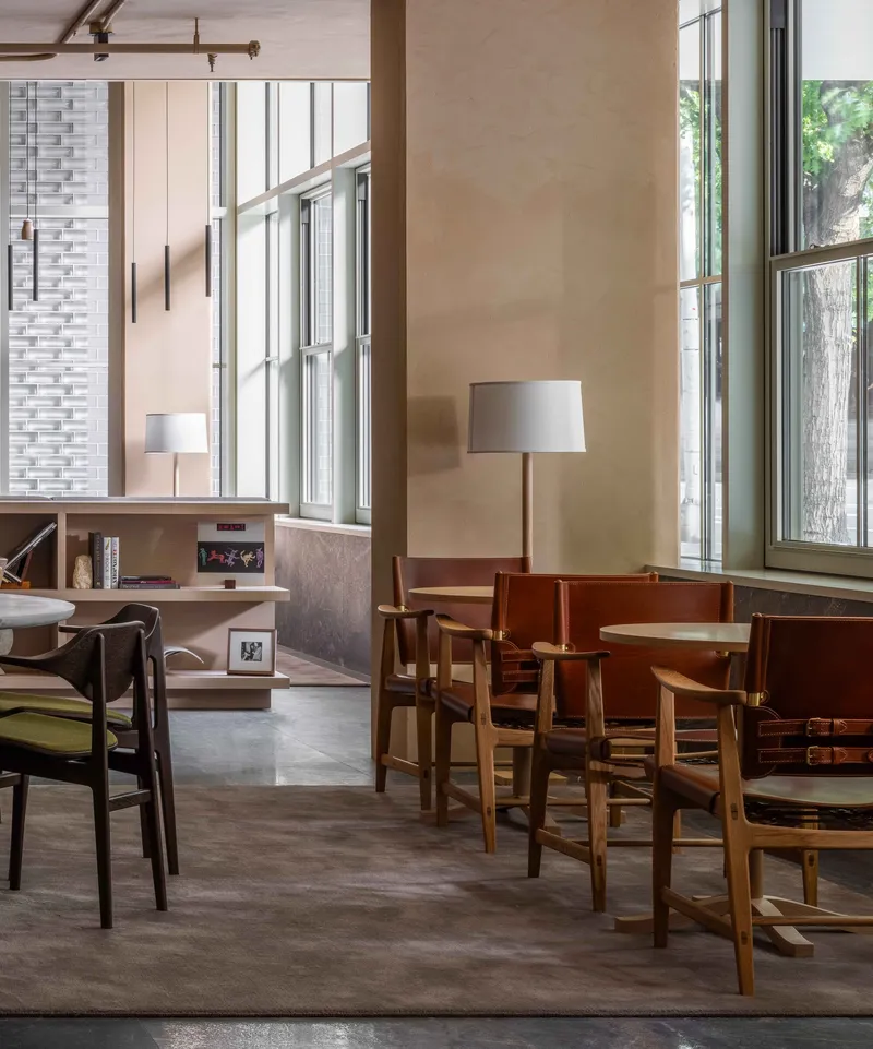 Lobby seating area with timber furniture beneath tall windows in afternoon light
