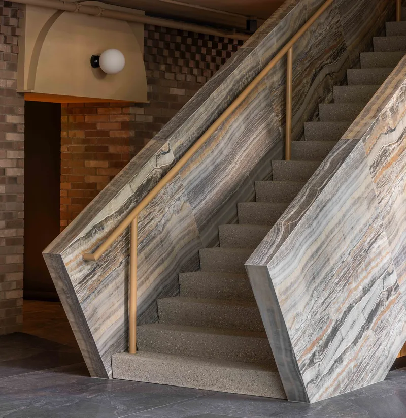 Terrazzo staircase with layered stone balustrade showing veined grey and amber striations