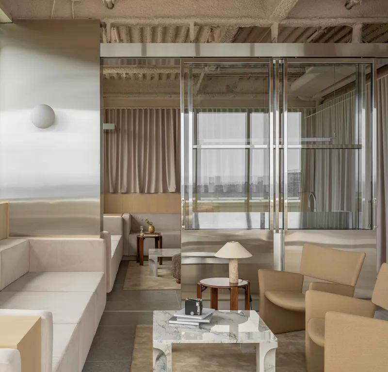 Interior lounge with exposed timber joists and steel framed glazing dividing adjacent spaces