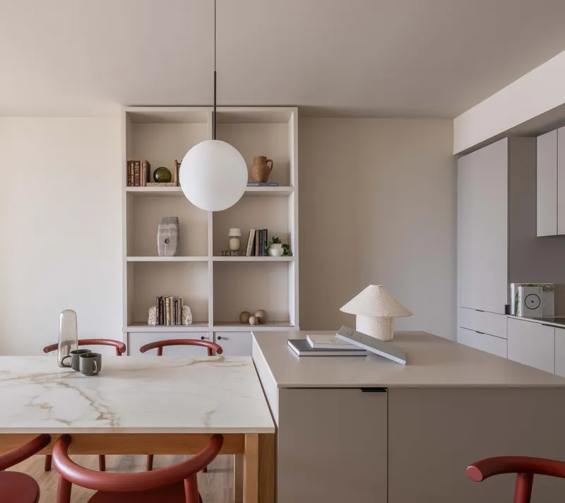 Open kitchen and dining area with marble table, built-in shelving, and spherical pendant light