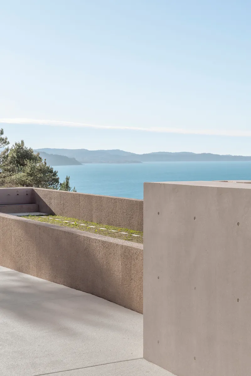Tiered concrete terraces framing a view across the bay toward layered blue mountains