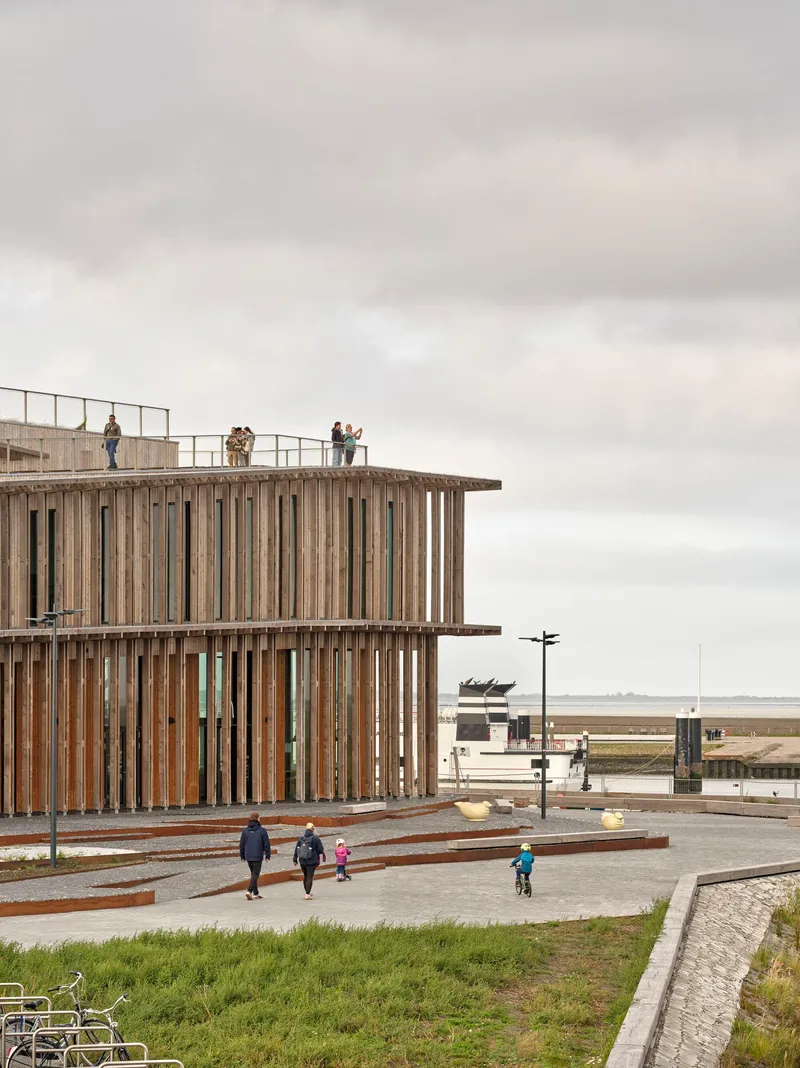 Corner detail of the timber-screened facade with visitors on the rooftop terrace and families below