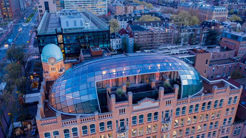 Aerial view of the curved glass roof structure atop a brick building at dusk