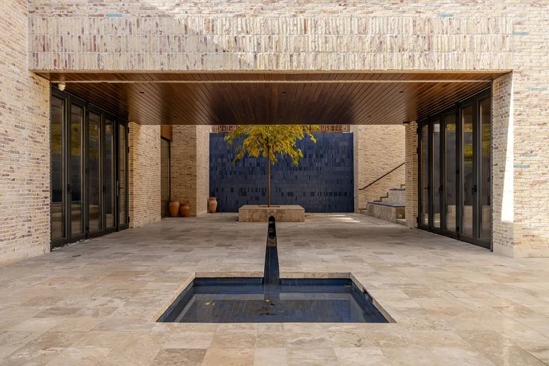Covered courtyard with timber ceiling, reflecting pool, and folding glass doors