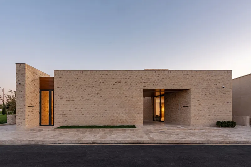 Street facade with variegated brick walls and recessed timber doorway under evening sky