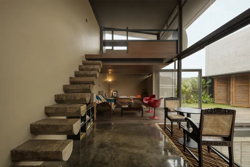 Interior living space with floating concrete staircase and double-height glazing overlooking the deck
