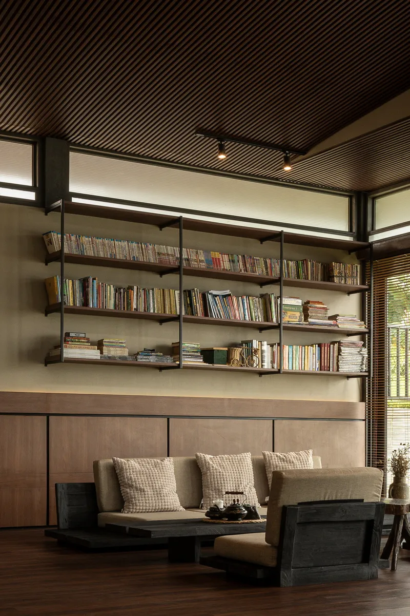Built-in bookshelf beneath clerestory windows with timber slat ceiling and afternoon sunlight